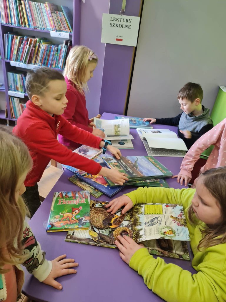 dzieci w bibliotece przeglądają bajki.