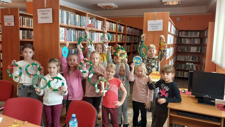 Grupa dzieci w bibliotece, recznie wykonane wieńce swiąteczne.