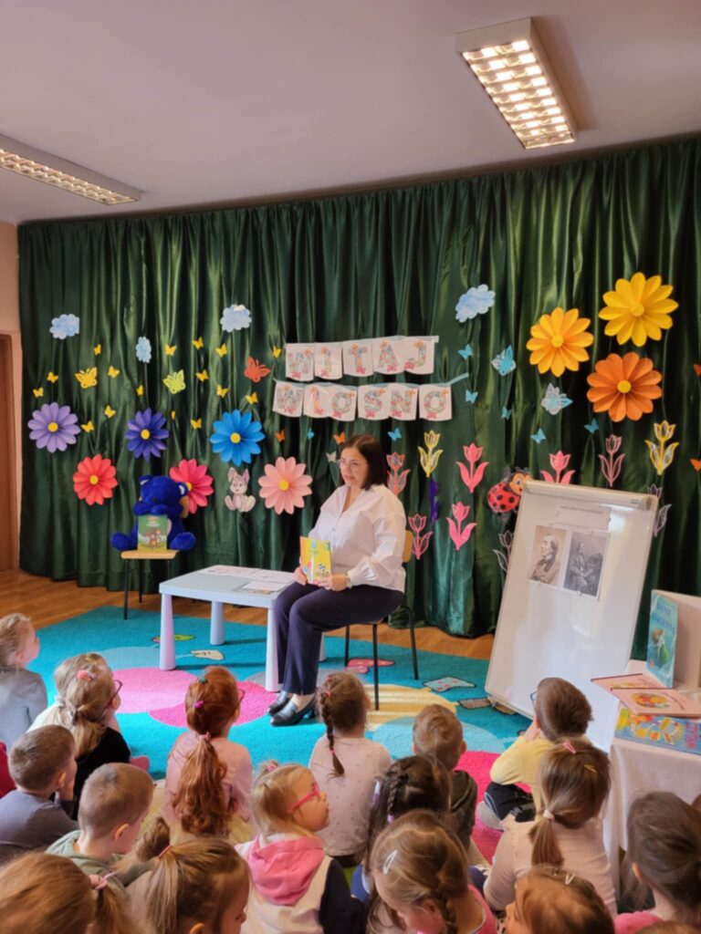 Dzieci w przedszkolu, pani bibliotekarka pokazuje książkę.